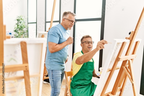 Group of middle age paint students drawing at art studio. Teacher looking student draw.