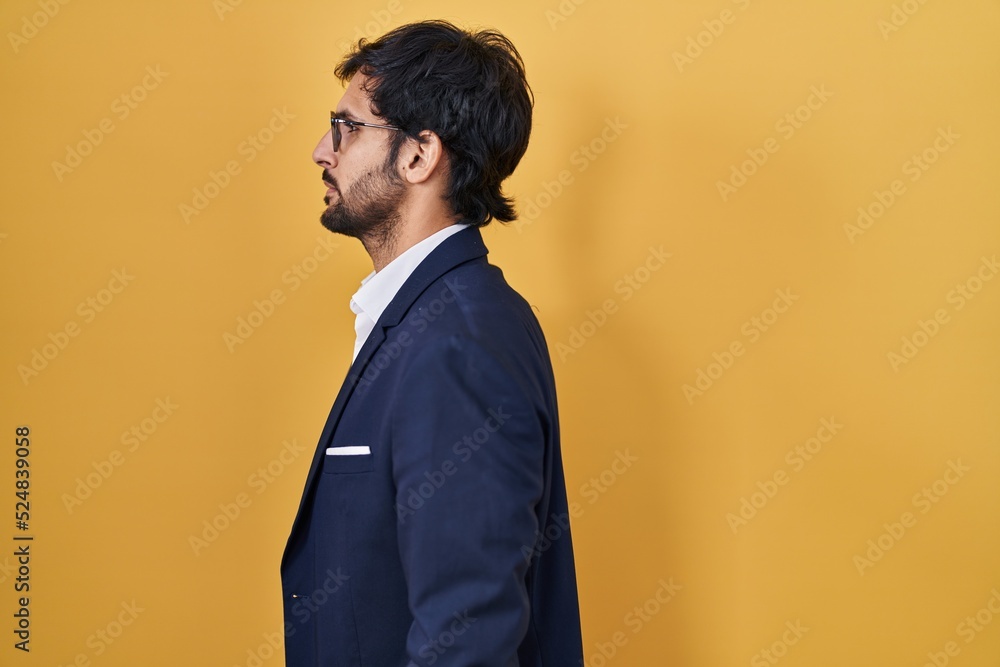 Handsome latin man standing over yellow background looking to side, relax profile pose with natural face and confident smile. Handsome latin man standing over yellow background looking to side, relax profile pose with natural face and confident smile.