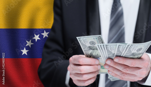Hands holding dollar money on flag of Venezuela photo