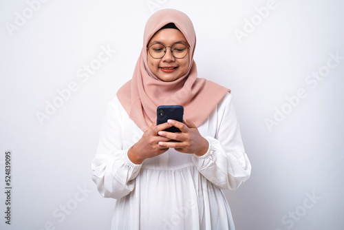 Young asian muslim woman smiling using mobile phone © Reza