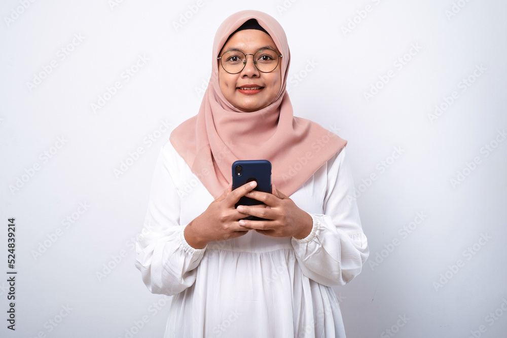 Young asian muslim woman smiling using mobile phone Young asian muslim woman smiling using mobile phone