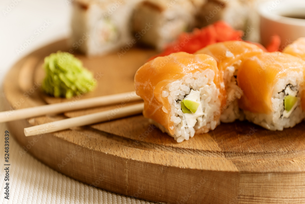 Set of delicious salmon philadelphia sushi roll served with wasabi cream and chopstick on wooden board Set of delicious salmon philadelphia sushi roll served with wasabi cream and chopstick on wooden board