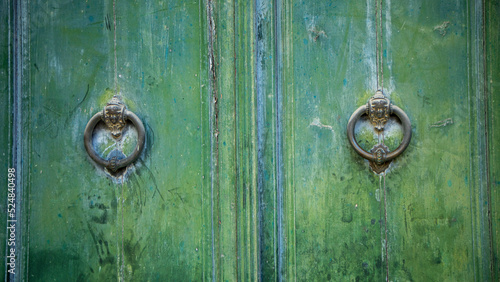 Obraz na plátně Old and worn double-leaf door with metal knockers and painted dark green