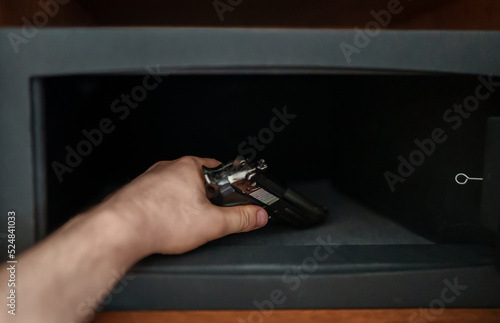 Man puts the weapon in the safe.