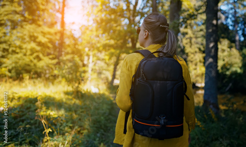 Woman tourist with backpack exploring forest. Back view.