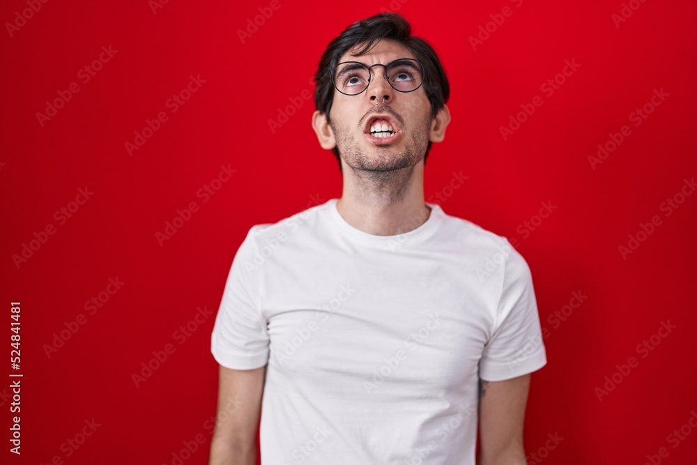 Young hispanic man standing over red background angry and mad screaming frustrated and furious, shouting with anger. rage and aggressive concept. Young hispanic man standing over red background angry and mad screaming frustrated and furious, shouting with anger. rage and aggressive concept.