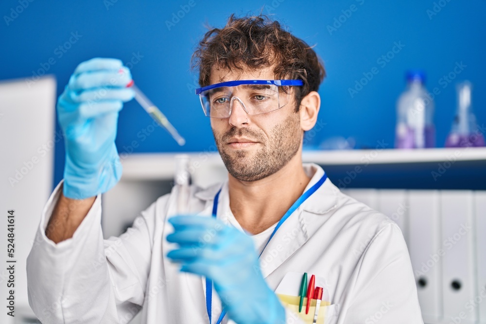 Young man scientist pouring liquid on test tube at laboratory Young man scientist pouring liquid on test tube at laboratory