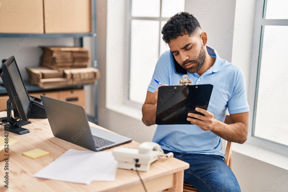Young hispanic man ecommerce business worker talking on the smartphone at office Young hispanic man ecommerce business worker talking on the smartphone at office
