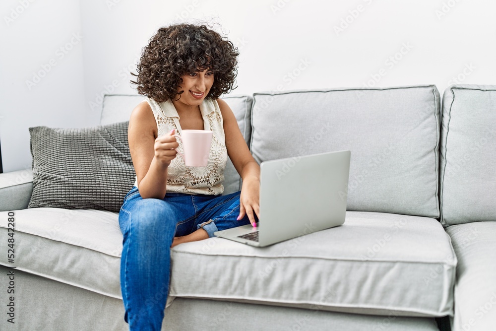 Young middle east woman drinking coffee using laptop at home Young middle east woman drinking coffee using laptop at home
