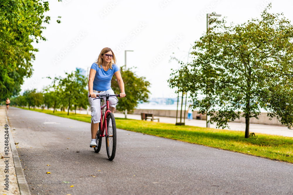 Woman riding bike in city park Woman riding bike in city park
