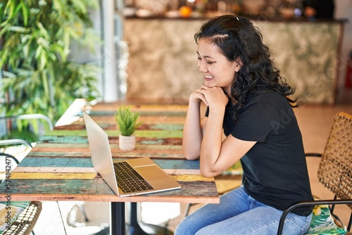 Young chinese woman using laptop sitting on table at restaurant