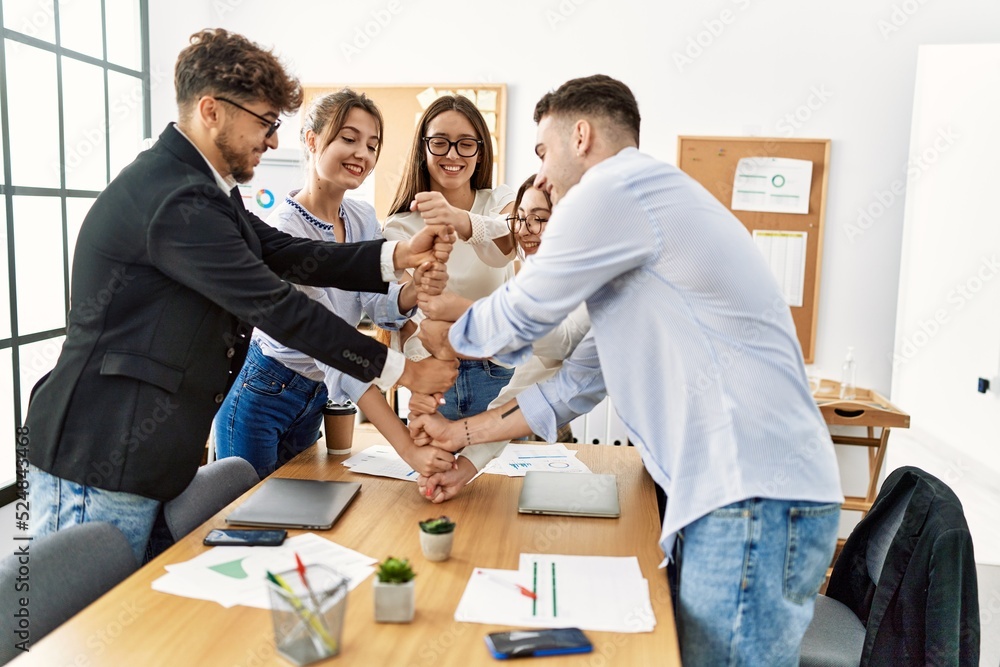 Group of young business workers smiling happy celebrating making tower with fists together at the office.