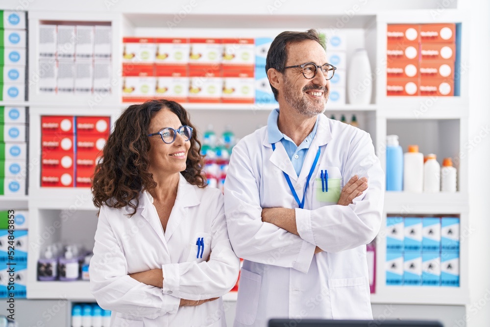 Man and woman pharmacists smiling confident standing with arms crossed gesture at pharmacy Man and woman pharmacists smiling confident standing with arms crossed gesture at pharmacy