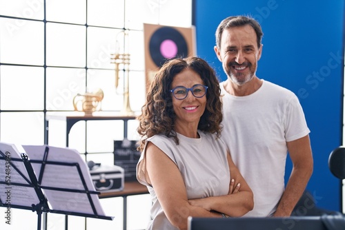 Man and woman musicians smiling confident standing with arms crossed gesture at music studio