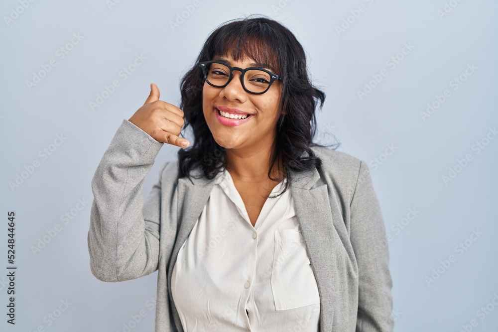 Hispanic woman standing over isolated background smiling doing phone gesture with hand and fingers like talking on the telephone. communicating concepts. Hispanic woman standing over isolated background smiling doing phone gesture with hand and fingers like talking on the telephone. communicating concepts.