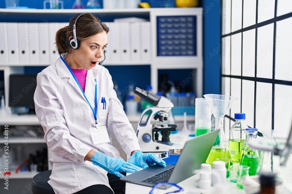 Hispanic woman working at scientist laboratory scared and amazed with open mouth for surprise, disbelief face Hispanic woman working at scientist laboratory scared and amazed with open mouth for surprise, disbelief face