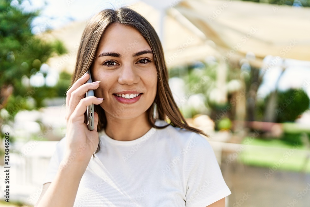 Young beautiful woman smiling happy outdoors on a sunny day having a conversation speaking on the phone