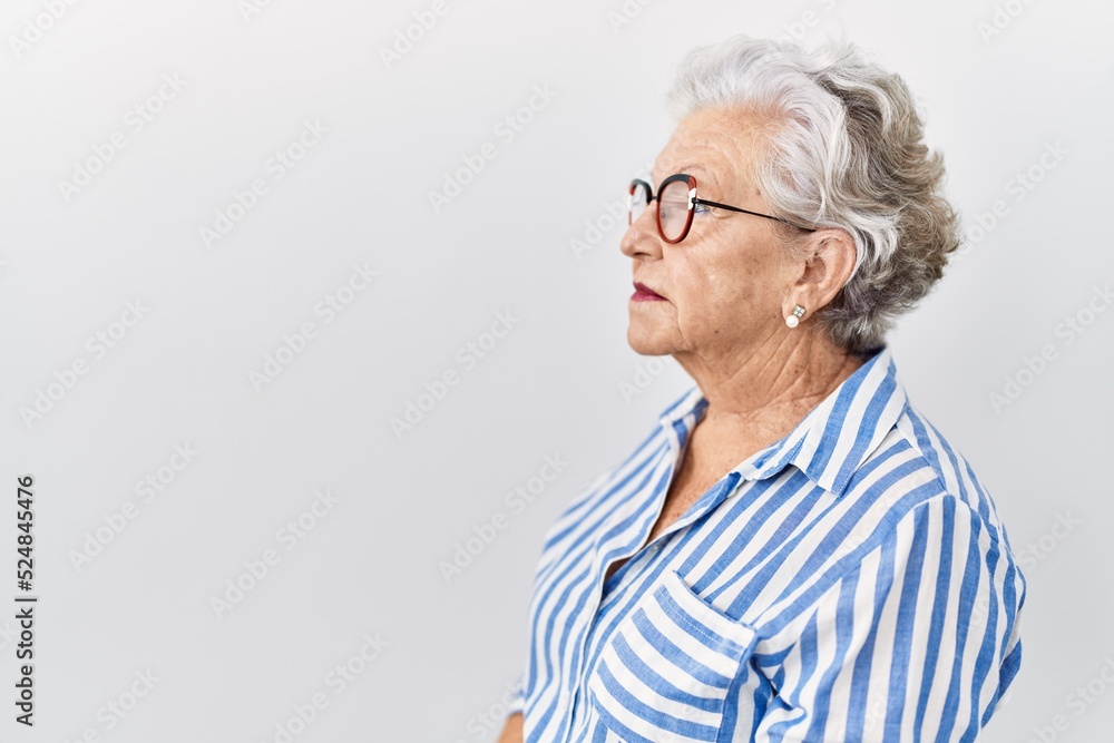 Senior woman with grey hair standing over white background looking to side, relax profile pose with natural face with confident smile. Senior woman with grey hair standing over white background looking to side, relax profile pose with natural face with confident smile.