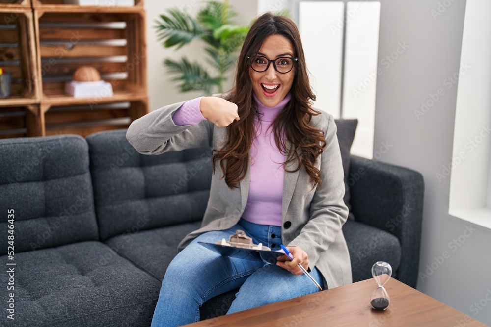 Young brunette woman working at consultation office looking confident with smile on face, pointing oneself with fingers proud and happy. Young brunette woman working at consultation office looking confident with smile on face, pointing oneself with fingers proud and happy.