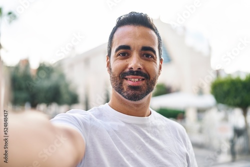 Young hispanic man smiling confident making selfie by the camera at street © Krakenimages.com