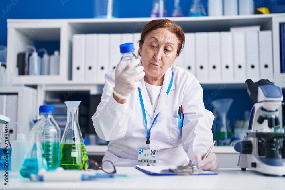 Senior woman scientist measuring liquid write on document at laboratory Senior woman scientist measuring liquid write on document at laboratory