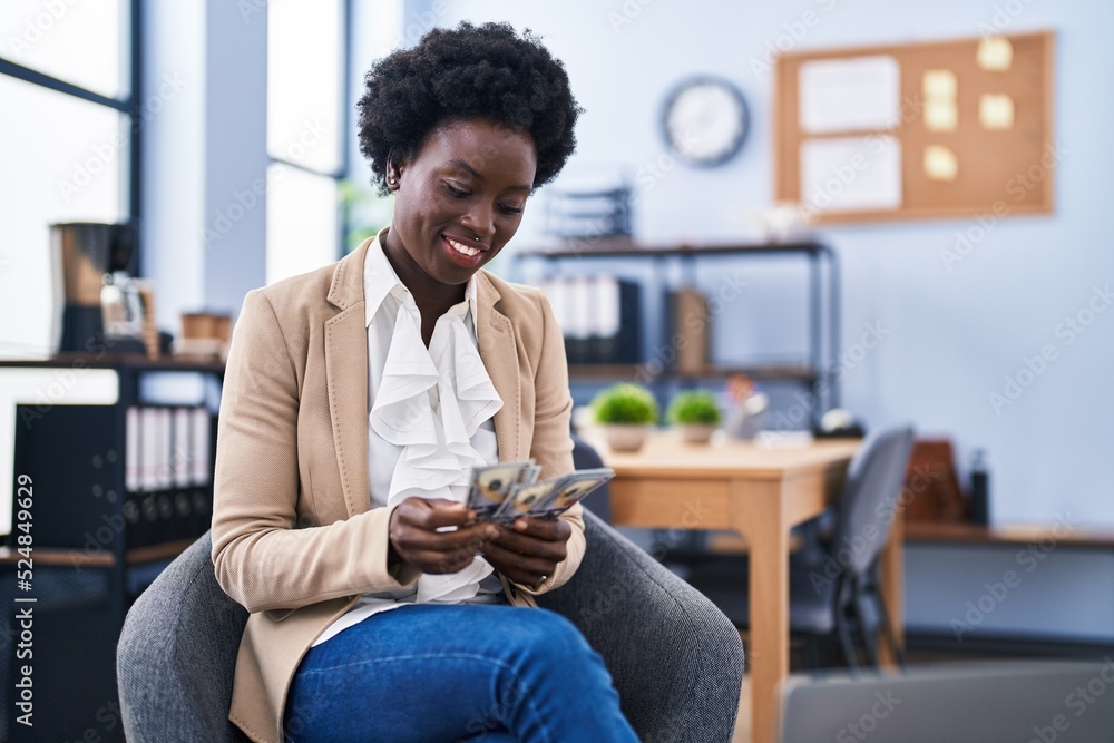 Young african american woman business worker counting dollars sitting on chair at office