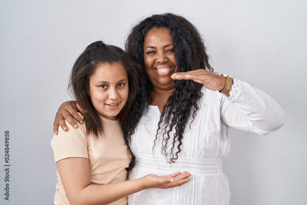 Mother and young daughter standing over white background gesturing with hands showing big and large size sign, measure symbol. smiling looking at the camera. measuring concept. Mother and young daughter standing over white background gesturing with hands showing big and large size sign, measure symbol. smiling looking at the camera. measuring concept.