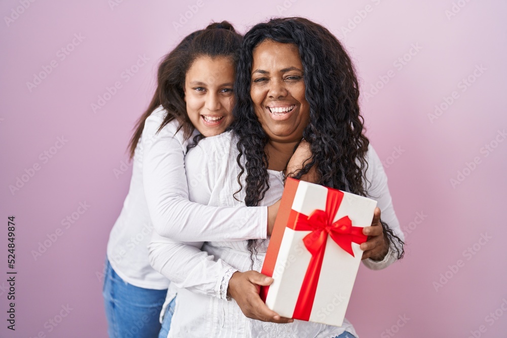 Mother and young daughter holding with presents smiling and laughing hard out loud because funny crazy joke. Mother and young daughter holding with presents smiling and laughing hard out loud because funny crazy joke.