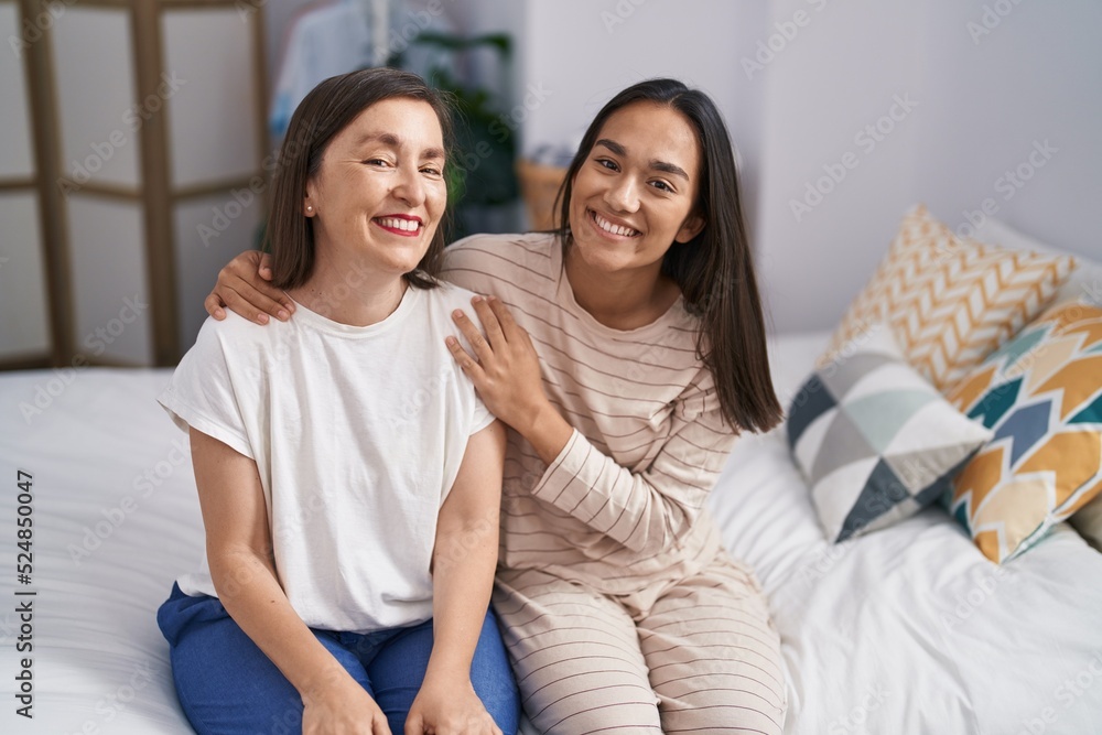 Two women mother and daughter hugging each other sitting on bed at bedroom Two women mother and daughter hugging each other sitting on bed at bedroom