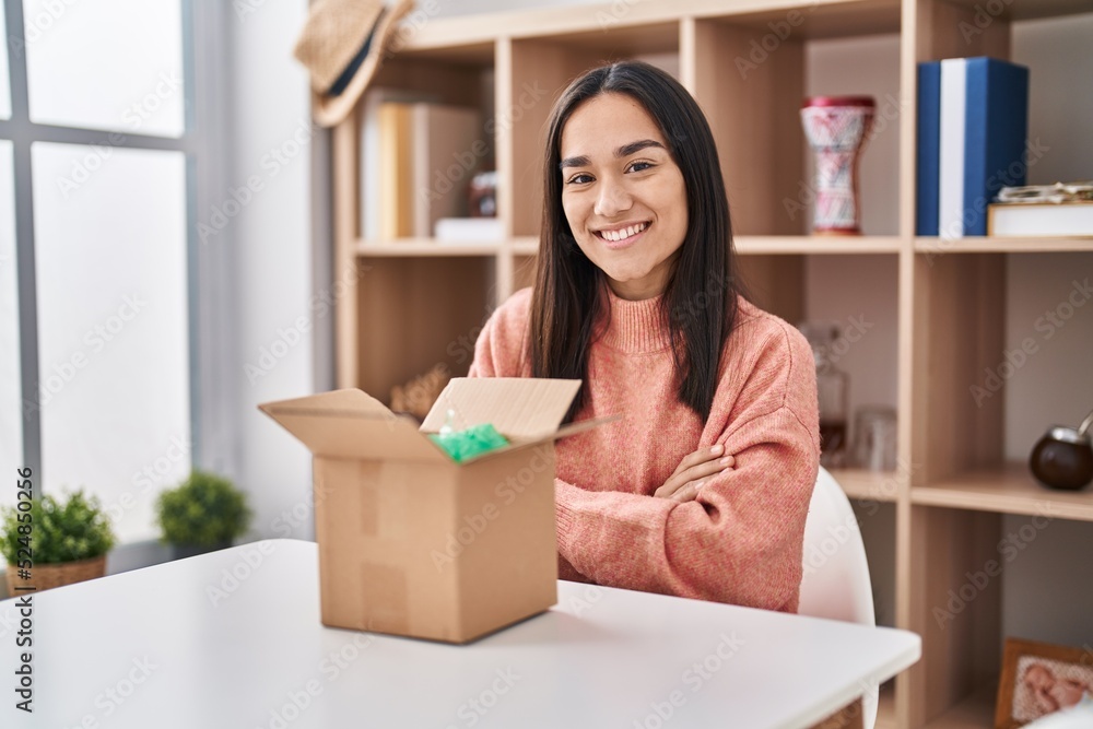 Young south asian woman opening cardboard box happy face smiling with crossed arms looking at the camera. positive person. Young south asian woman opening cardboard box happy face smiling with crossed arms looking at the camera. positive person.