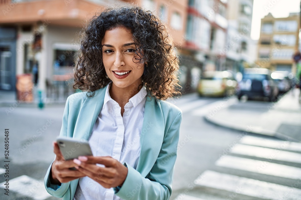 Young hispanic business woman wearing professional look smiling confident at the city using smartphone Young hispanic business woman wearing professional look smiling confident at the city using smartphone