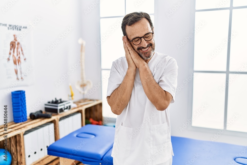 Middle age man with beard working at pain recovery clinic sleeping tired dreaming and posing with hands together while smiling with closed eyes. Middle age man with beard working at pain recovery clinic sleeping tired dreaming and posing with hands together while smiling with closed eyes.