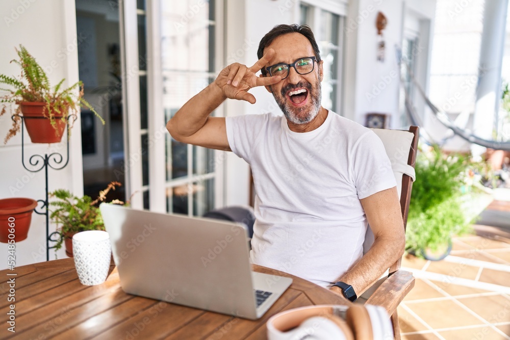 Middle age man using computer laptop at home doing peace symbol with  fingers over face, smiling cheerful showing victory Stock-Foto | Adobe Stock