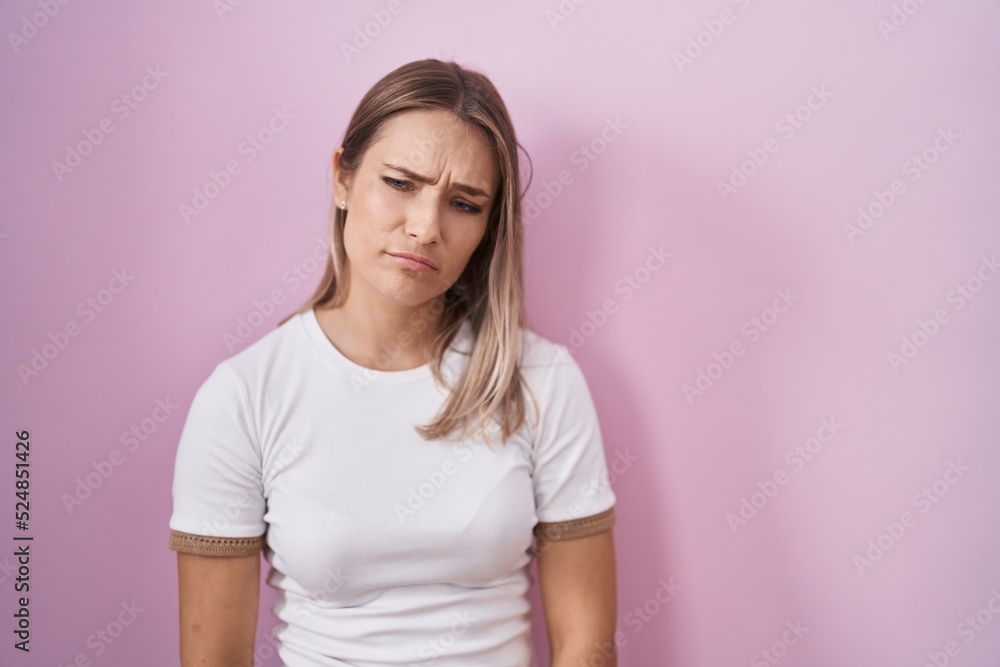 Blonde caucasian woman standing over pink background depressed and worry for distress, crying angry and afraid. sad expression. Blonde caucasian woman standing over pink background depressed and worry for distress, crying angry and afraid. sad expression.