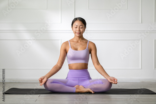 Calm of Attractive Asian woman practice yoga lotus pose to meditation in bedroom after wake up in the morning Feeling so comfortable and relax at home. Health care and Exercise at home Concept