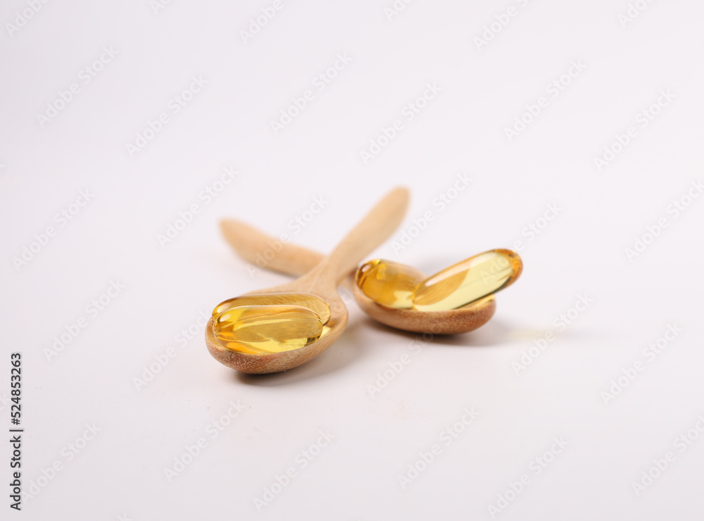 fish oil capsules, wood spoon on white background and supplements concept fish oil capsules, wood spoon on white background and supplements concept