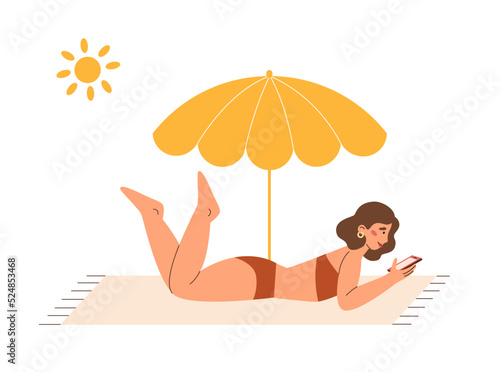 Pretty girl lying on a beach towel with phone and sunbathing 