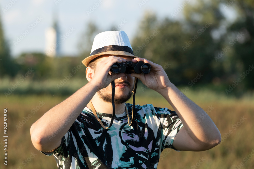 Obraz premium The young birdwacher with binocular obseving bird migration on the field