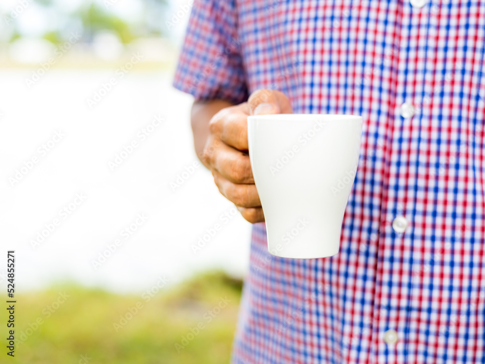 Close up of a hand of man holding a coffee cup standing at home Close up of a hand of man holding a coffee cup standing at home