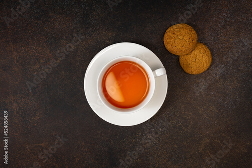 A cup of tea and coockies and honey on  dark background. View from above. photo