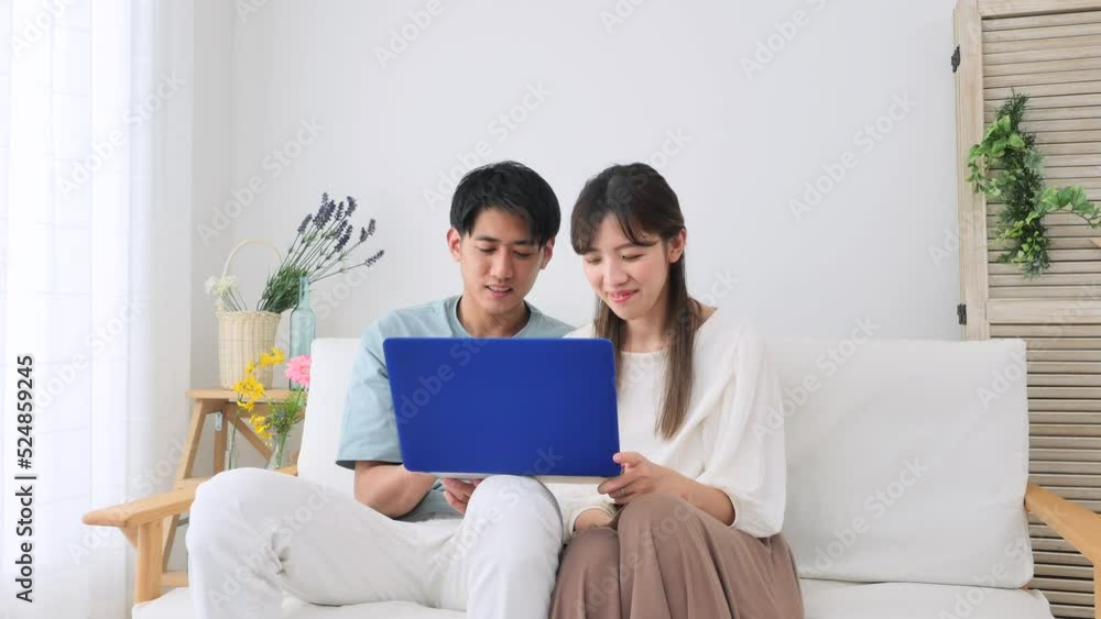 リビングでノートパソコンを見るカップル リビングでノートパソコンを見るカップル
