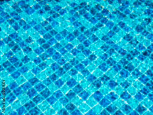 Blurred pool background. Blurry on top view of empty of blue mosaic tiles grid pattern in swimming pool. Empty space on the water surface, summer background.