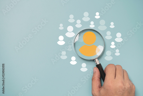 Schilderij op canvas Hand holding magnifier glass with yellow person icon among white people icons for Customer focus group ,recruitment and human development concept