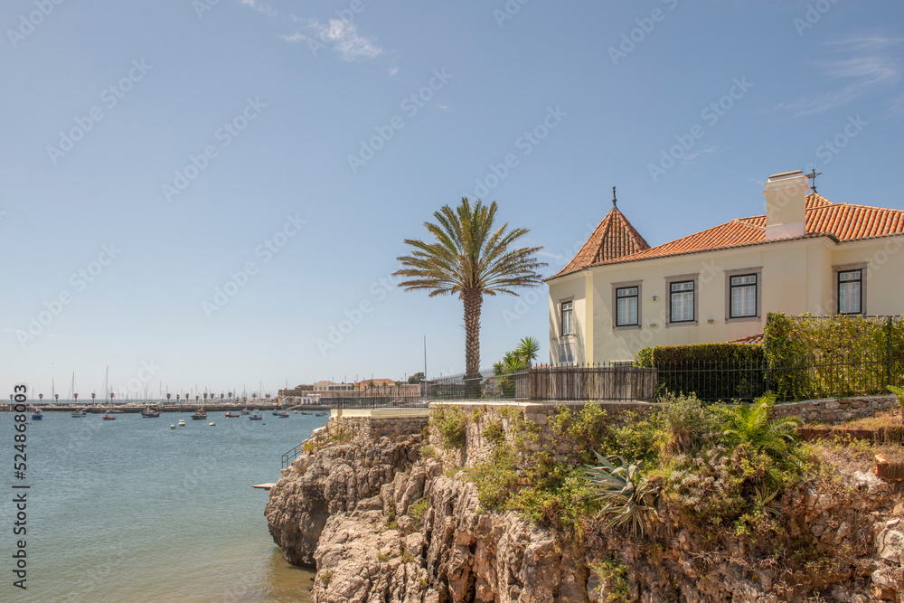 Nice low house on a cliff at the edge of the sea near a recreational pier on the coast of Estoril Nice low house on a cliff at the edge of the sea near a recreational pier on the coast of Estoril