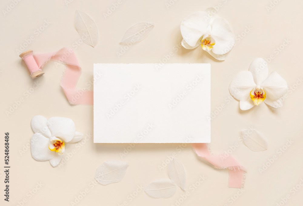 Blank card near white orchid flowers and pink silk ribbons on light beige, Wedding mockup
