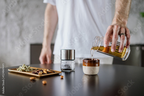 man prepare chinese tea in glass infuser at home kitchen photo