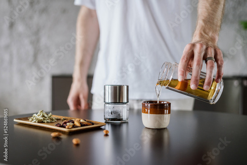 Fotografie man prepare chinese tea in glass infuser at home kitchen