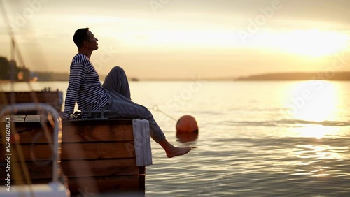 sailor or yachtsman is admiring dawn in early morning on yachts moorage in summer