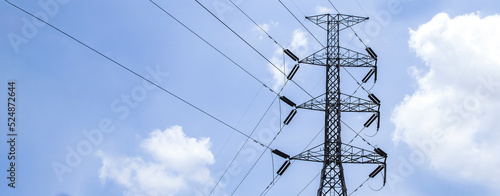 High voltage poles with sky and clouds in the background.