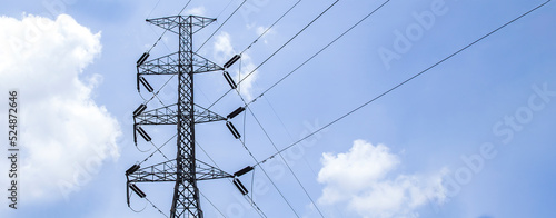 High voltage poles with sky and clouds in the background.